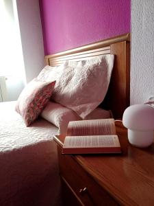 un letto con cassettiera in legno e un libro sopra di Pensión QuintAna a Prellezo