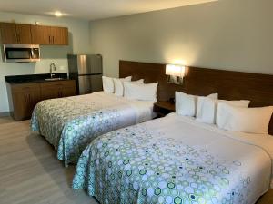 a hotel room with two beds and a kitchen at HomeTowne Studios by Red Roof East Lansing - Okemos in Okemos