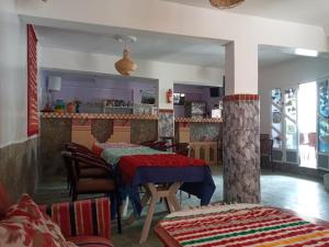 a living room with two tables and a kitchen at Auberge des lacs in Imilchil