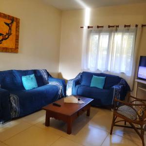 Sala de estar con 2 sofás azules y mesa de centro en Chale Buzios Praia Rasa, en Búzios