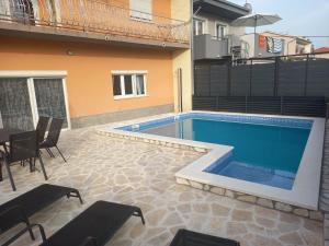 a swimming pool with chairs and a table and a building at Apartment Gajo with swimming pool near Split in Srinjine