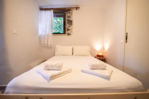 a bedroom with a white bed with towels on it at Feneri 3 -Cozy rustic Apt 20' from Elafonisi beach in Perivólia