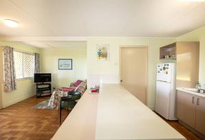 een keuken en een woonkamer met een wit aanrecht bij ARCADIA -Straddie original 3 bedroom house with ocean views in Point Lookout +2 foto's