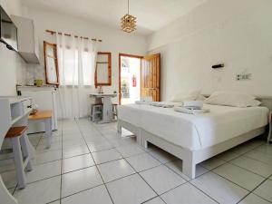 a bedroom with a large white bed and a kitchen at Emilia Apartments in Elounda