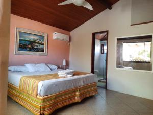 a bedroom with a bed with a painting on the wall at Casa Beto Búzios in Búzios