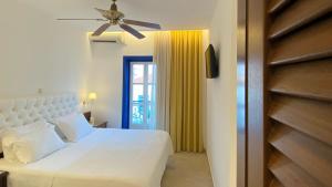 a bedroom with a white bed and a ceiling fan at Armata Boutique Hotel in Spetses