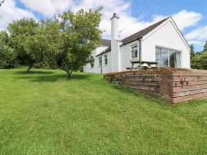 a white house with a brick wall in the yard at Brae of Airlie Farm in Kirkton of Airlie