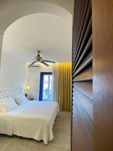 a bedroom with a white bed and a ceiling fan at Armata Boutique Hotel in Spetses