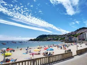 Grupa ludzi na plaży z parasolami w obiekcie Hotel Gran Proa Playa Raxó w mieście Raxo