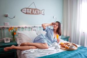 a woman laying on a bed with a tray of food at Hotel Gran Proa Playa Raxó in Raxo