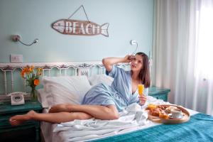 kobieta leżąca na łóżku z tacą z jedzeniem w obiekcie Hotel Gran Proa Playa Raxó w mieście Raxo
