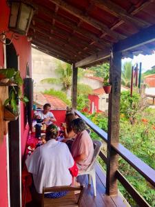 a group of people sitting at a table on a porch at Casa Vermelha Búzios in Búzios +30 photos