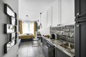 a kitchen with white cabinets and a brick wall at Stylowe king studio, metro Słodowiec, parking, park in Warsaw