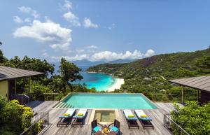 uitzicht op een zwembad met stoelen en een strand bij Four Seasons Resort Seychelles in Baie Lazare Mahé