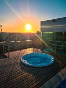 una bañera de hidromasaje en una terraza con vistas a la puesta de sol en el fondo en Paradiso Corporate, en Cabo Frío
