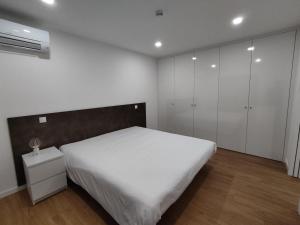 a bedroom with a white bed and white cabinets at Quinta do Gestal - Soutelo in Vila Verde