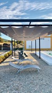 a group of chairs under a pavilion with a pool at Casas do Apeadeiro in Vimieiro