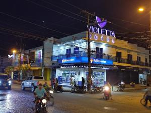 a building on a street at night with people on motorcycles at HOTEL VIOLETTA Cereté in Cereté