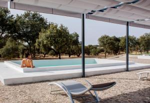 a woman sitting in a pool with two chairs at Casas do Apeadeiro de Evoramonte in Vimieiro