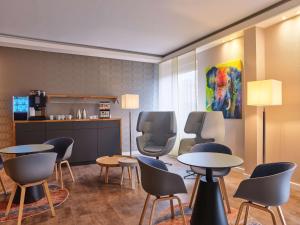 uma sala de espera com mesas e cadeiras e uma cozinha em Best Western Hotel Prisma em Neumünster