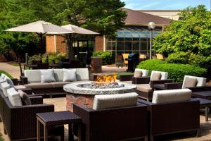 a patio with a fire pit and chairs and an umbrella at Sonesta Select Boston Milford in Milford