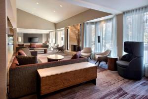 a living room with a couch and chairs and a television at Sonesta Select Boston Milford in Milford