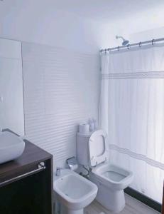 a white bathroom with a toilet and a sink at Los Bungalows in José Ignacio