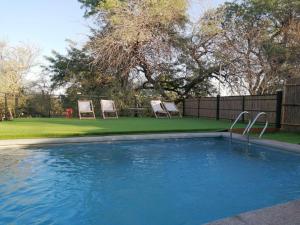 a swimming pool with two chairs in a yard at Aji Verde Hostel San Pedro in San Pedro de Atacama