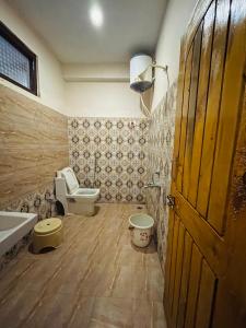 ein Bad mit einem WC, einem Waschbecken und einer Tür in der Unterkunft The Riverwoods - Cafe & Stay in Kasol
