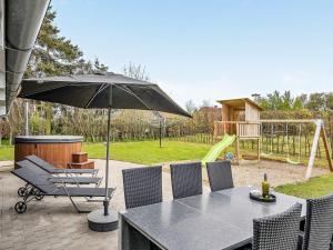 een tafel en stoelen met een parasol en een speeltuin bij 14 person holiday home in Sydals in Høruphav