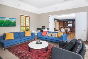 a living room with blue couches and a table at French City Mansion - Christchurch Luxury Home in Christchurch