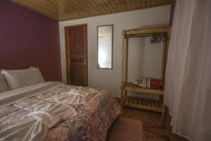 una camera con letto e specchio di Chalés Cerejeira a Visconde De Maua