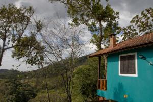 a blue house with a view of the mountains at Chalés Cerejeira in Visconde De Maua