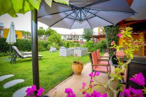 eine Terrasse mit einem Sonnenschirm und Stühlen sowie einem Hof in der Unterkunft Pura Villa- Buganvillas Ayamonte in Ayamonte