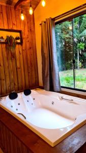 bañera grande en una habitación con ventana en Pousada Recanto dos Canyons en Praia Grande