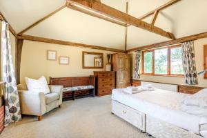 a bedroom with a bed and a chair at The Cart Lodge in Halesworth