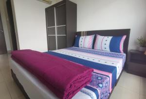 イポーにあるIpoh Majestic R&C Homestay 1のベッドルーム1室(カラフルなシーツと枕のベッド1台付)