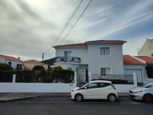 dos autos estacionados frente a una casa blanca en Casa da Isabelinha, en Ponta Delgada