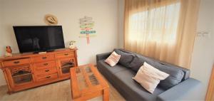 a living room with a black leather couch and a television at Apartamentos La Libertad Estepona in Estepona