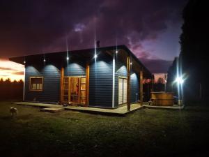 une petite maison avec des lumières allumées la nuit dans l'établissement Cabaña Relmu Osorno con tinaja, à Pichil