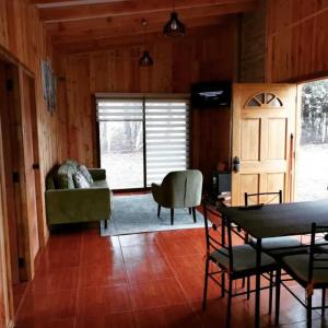 - un salon avec un canapé, une table et des chaises dans l'établissement Cabaña Relmu Osorno con tinaja, à Pichil