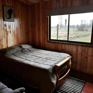 PichilにあるCabaña Relmu Osorno con tinajaの窓のある部屋にベッドがある寝室