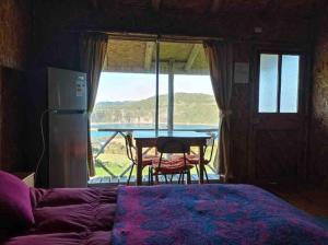a bedroom with a bed and a table with a view of the water at Cabaña pumillahue rural in Ancud