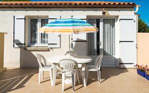 - une table et des chaises avec un parasol sur la terrasse dans l'établissement Lagrange Vacances Les Maisons de Saint Georges, à Saint-Georges-de-Didonne