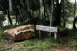 a sign sitting next to a large rock at Casa de Campo da Vó in Urupema