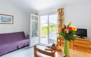 uma sala de estar com um sofá roxo e um vaso de flores em Lagrange Vacances Le Clos des Chênes em Les Mathes