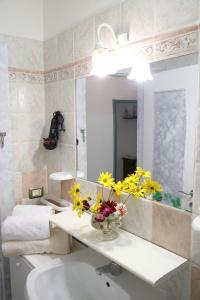 a bathroom with a sink and a vase of flowers on a counter at B&B Natalia in Gualdo Tadino