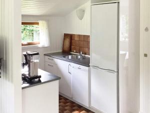 a white kitchen with a refrigerator and a sink at 6 person holiday home in Idestrup in Marielyst