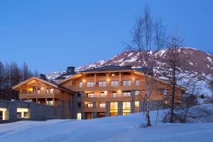 un grand bâtiment dans la neige la nuit dans l'établissement Lagrange Vacances l'Alpenrose, à L'Alpe-d'Huez