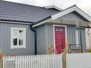 una casa gris con una puerta roja y una valla en Holiday home SÖLVESBORG XVI, en Sölvesborg